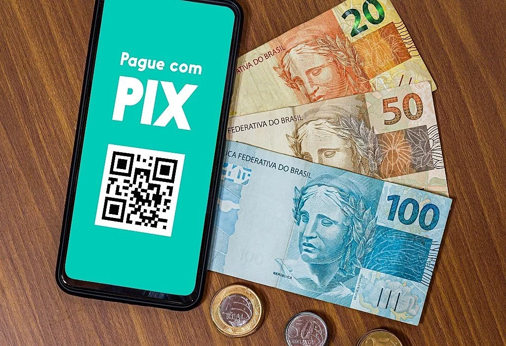 Celular exibindo Pix ao lado de cédulas de 100 reais, simbolizando empréstimo de 500 reais aprovado e liberado via Pix